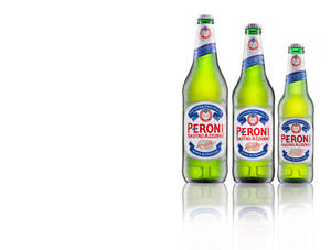 三瓶Peroni啤酒瓶帶有水珠，放在白色反射表面上。