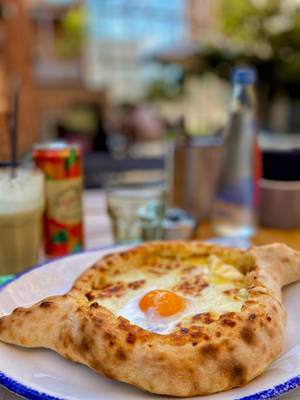 藍邊白碟上的 khachapuri 配流心蛋黃，在戶外桌上。