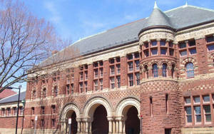 歷史悠久的紅磚大學建築，設有拱形入口和石塔。 — 藍天 壁紙