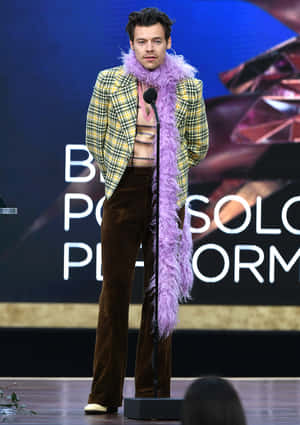 Harry Styles 在舞台上穿著黃色格紋外套和紫色羽毛圍巾。 — 哈里·斯泰爾斯 壁紙