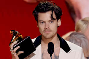 Harry Styles 身穿白色西裝，在舞台上手持格林美獎。 — 哈里·斯泰爾斯 壁紙