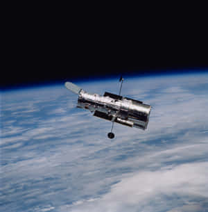 哈勃太空望遠鏡繞地球運行，下方有雲層，上方是漆黑太空 — 太空 壁紙