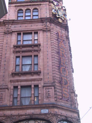 宏偉褐石建築的角落，帶有「HARRODS」霓虹招牌。 — 晴朗天空 壁紙