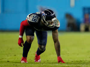 身穿田納西泰坦隊制服的美式足球員在夜間蹲在球場上。 — NFL 美式足球 GIF 壁紙