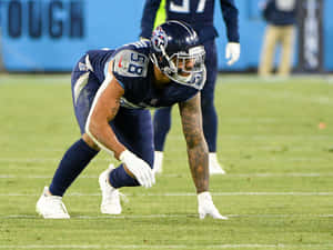 身穿海軍藍制服的美式足球員在夜間草地上蹲伏。 — NFL 美式足球 GIF 壁紙