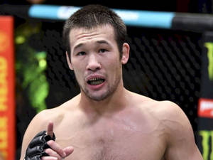 一位男性MMA選手在籠中比賽時指向前方。