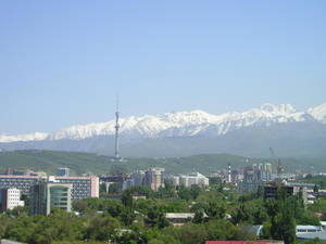城市，白雪覆蓋的山脈和綠色山丘，天空清澈湛藍。 — 山脈 壁紙