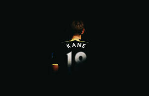 足球員背面，身穿黑色球衣，上有白色 'KANE 19'。