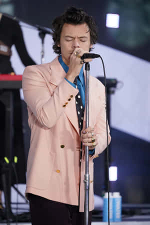 Harry Styles 在舞台上穿著粉紅色西裝外套和波點襯衫唱歌。 — 哈里·斯泰爾斯 壁紙