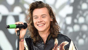 Harry Styles 微笑著在舞台上拿著麥克風。