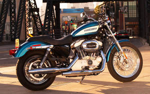 日落時分，青綠色Harley-Davidson電單車停泊在橋附近的行人路上。