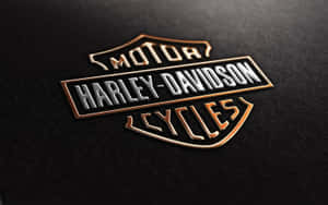 Harley-Davidson標誌徽章，在黑色紋理表面上帶有金色和銀色細節。
