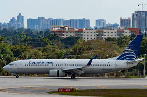 Copa Airlines 飛機在機場跑道上，背景有城市和樹木