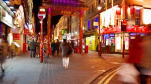 唐人街夜晚街道場景，帶有發光招牌和模糊的行人。 — 極光 壁紙