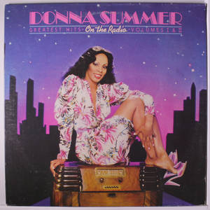 Donna Summer 穿著花卉圖案連衣裙，坐在復古收音機上，背景是夜晚城市天際線。 — 復古gif 壁紙