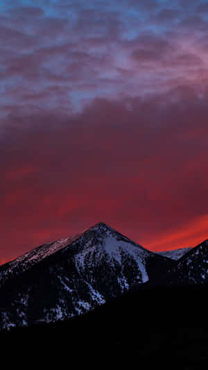 暮色中白雪覆蓋的山峰，火紅與深紫的天空