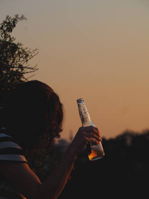 日落時分手持啤酒瓶的人，帶有剪影和樹枝。 — 女孩 壁紙