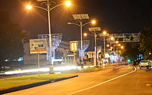 夜晚的城市街道，閃爍的路燈和節日裝飾，模糊的車燈光線劃過道路。
