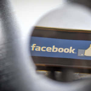 透過圓形開口看到的Facebook標誌，金屬邊緣模糊。