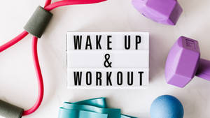 健身器材圍繞著一個寫著 wake up and workout 的標誌排列。