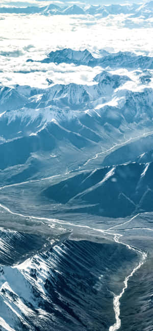 積雪的山脈聳立於雲層之上，下方有深邃的山谷。