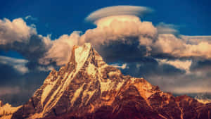 戲劇性日落天空下的白雪覆蓋山峰和透鏡狀雲。