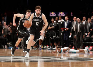 布魯克林籃網隊籃球運動員在比賽中運球，防守球員在附近。