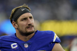 NFL四分衛身穿帶有隊長標誌的藍色球衣，在比賽中顯得專注。