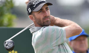 揮桿中的男性高爾夫球手，戴著 Titleist 帽子和條紋襯衫。