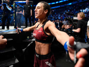 女MMA拳手在UFC八角籠中張開雙臂慶祝勝利。