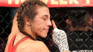 身穿紅色上衣的女性MMA拳手在八角籠內比賽後觸摸臉部。
