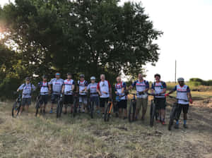 一群山地車手在日落時於樹下與單車合照。