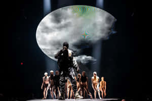 一位表演者在舞台上，與舞者在戲劇性燈光和超現實雲投影下。