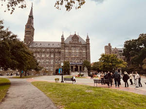 學生們走近一座帶有鐘樓的歷史石造大學建築。