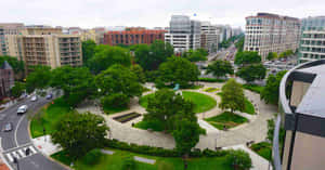 俯瞰一個圓形綠色公園，有樹木和小徑，位於被建築物包圍的城市中。