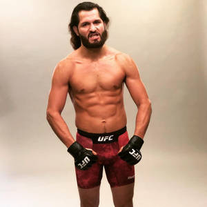 一個肌肉發達、留鬍鬚的UFC拳手，穿著紅色短褲和黑色手套。