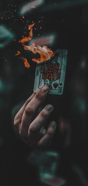 手拿著燃燒的紅心K牌，火花四濺