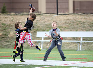 年輕男孩在陽光明媚的日子裡在草地上玩奪旗式美式足球。