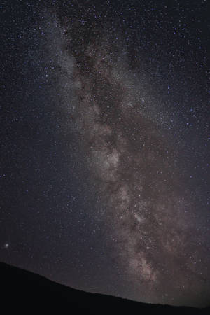 夜晚，銀河系在山脈上方發光。