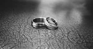 黑白龜裂皮革表面上的兩枚結婚戒指。