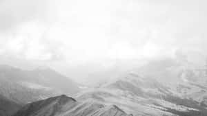寧靜的黑白山景，有霧氣繚繞的山谷和陰天天空。 — iMac 壁紙