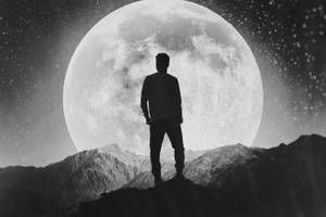 一個人的剪影站在山頂上，下方是巨大的月亮和星星。