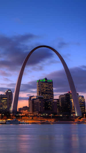 暮色中點亮的 Gateway Arch，城市天際線和河流倒影