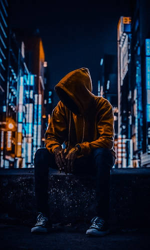 一個穿連帽衫的人夜晚獨自坐在城市窗台上，下方是發光的霓虹燈。 — 霓虹 壁紙