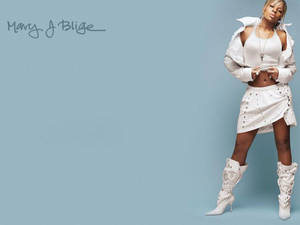 Mary J Blige 身穿白色服裝站在藍色背景前。