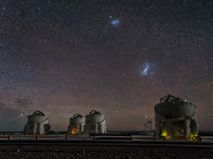 星空下四個天文台圓頂，可見銀河和星雲。 — 太空美學 GIF 壁紙