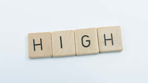 四個木塊在白色表面上拼出 HIGH。 — 天際線 壁紙