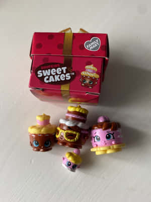 四個Shopkins Sweet Cakes玩具及其包裝在白色背景上。 — iPad Pro 13 壁紙