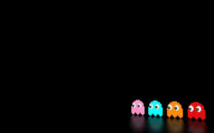 四個發光的 Pac-Man 鬼魂排列在黑暗的表面上。 — 迷幻暗黑風格 壁紙