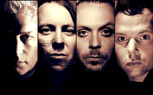 四位男士在戲劇性燈光下，頭髮隨風飄揚，表情強烈。 — OLED 壁紙